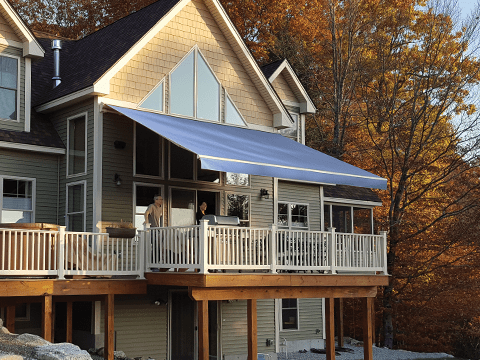 An open Sunesta awning provides cool shade for a Northeastern home during the fall season